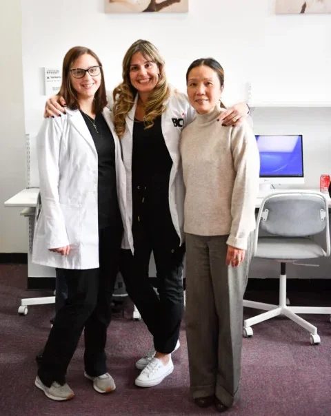 Three women smiling in a medical office environment